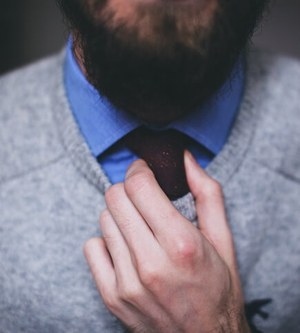 A man in a suit adjusts his tie.